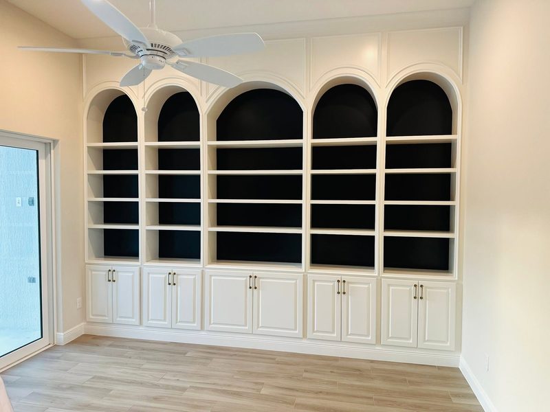 Painted built-in bookcases with arched openings and cabinet doors below