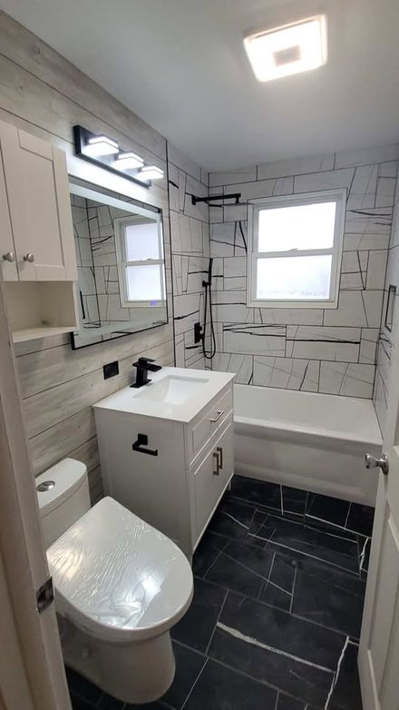 Small bathroom with a white vanity, wall cabinet, framed mirror and plank wall