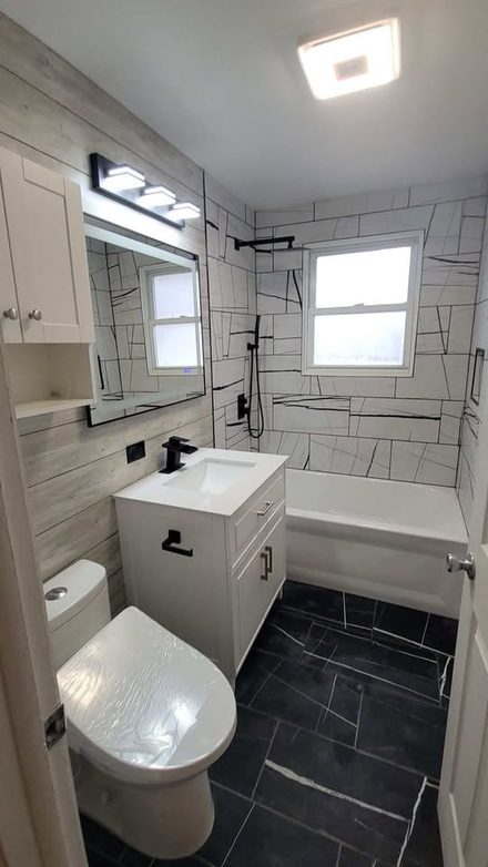 Finished bathroom with a white vanity, framed mirror, wall cabinet and plank wall
