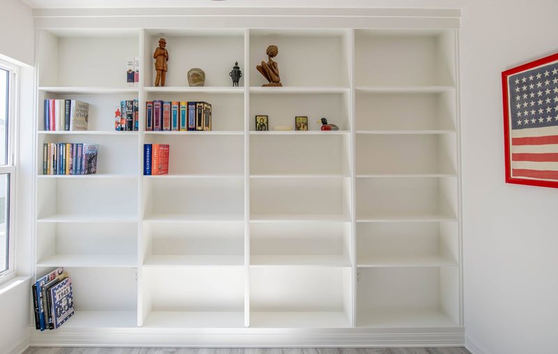 White floor-to-ceiling built-in bookcase wall with adjustable shelving