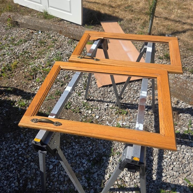 Two oak cabinet door frames laid out on sawhorses