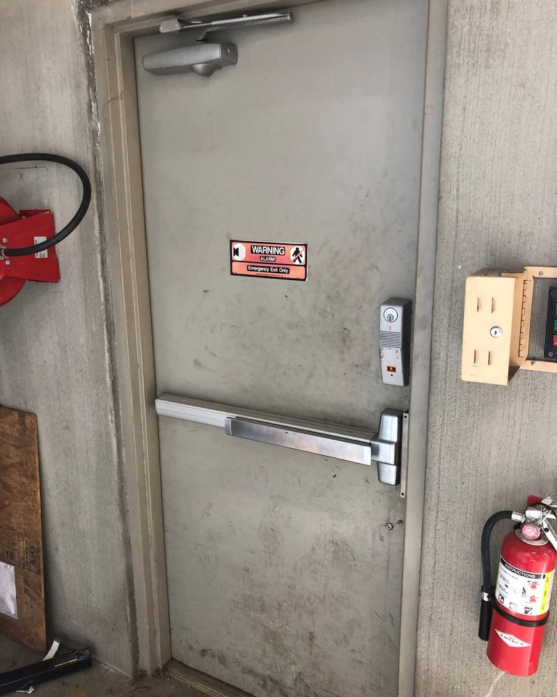 Overhead door closer and push bar on a commercial exit door
