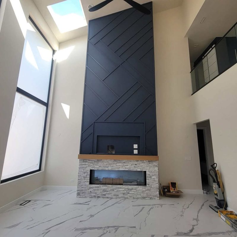 Two-storey navy feature wall with diagonal applied battens above a stone fireplace and a wood mantel