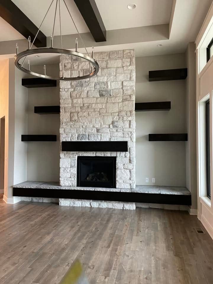Black floating shelves and mantel around a stone fireplace