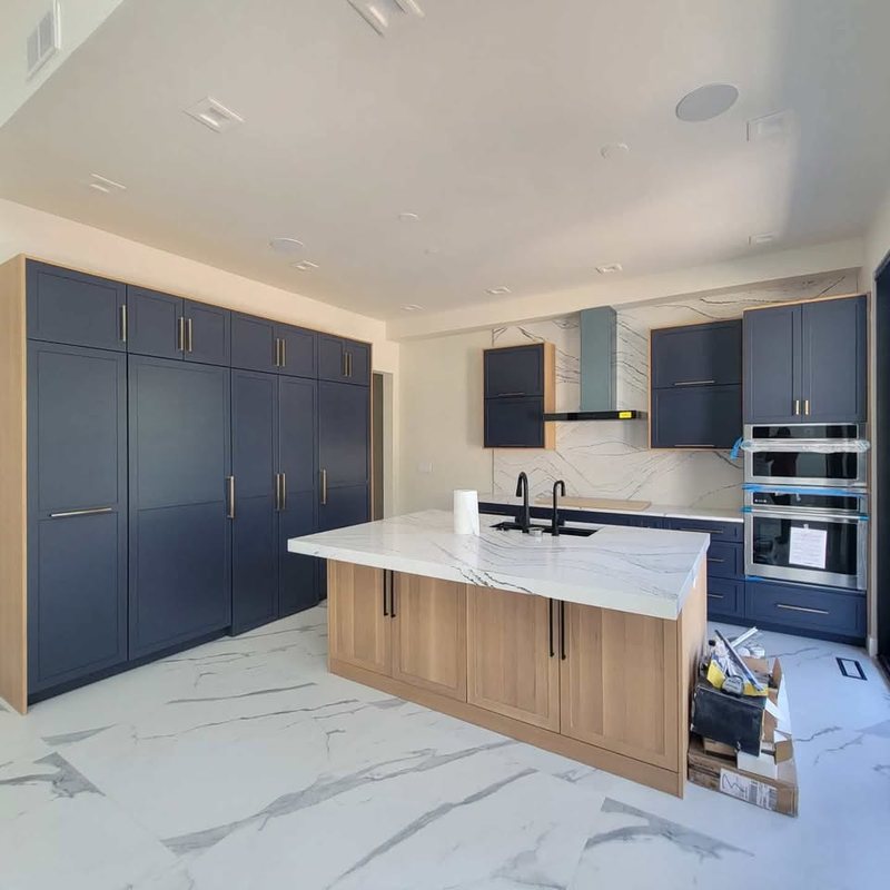 Navy slab-front kitchen cabinets with a white oak island and stone countertop