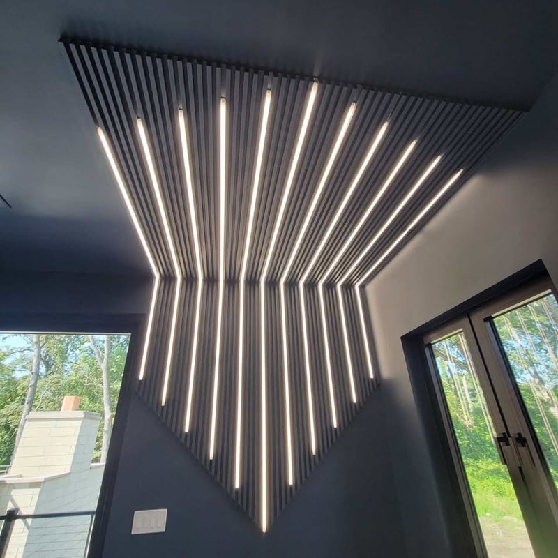 Slatted ceiling panel with recessed light strips fanning out across a dark ceiling