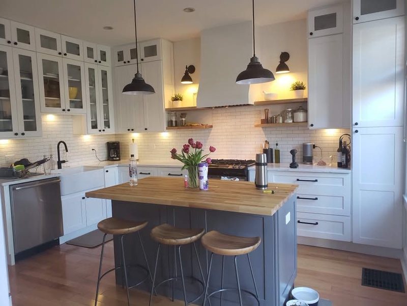 White kitchen with glass-front uppers and a butcher block island