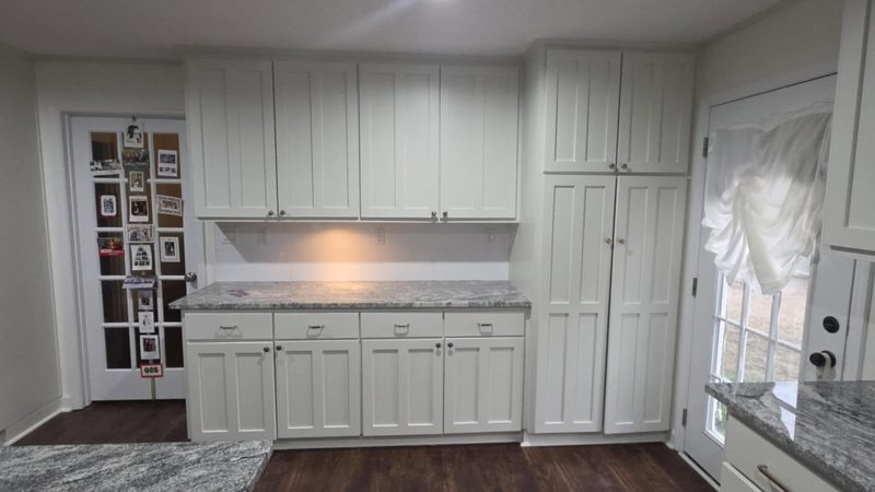 Finished white kitchen with wall cabinets, a tall pantry and base cabinets